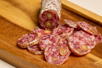 slices of fuet salami with walnuts on a wooden chopping board