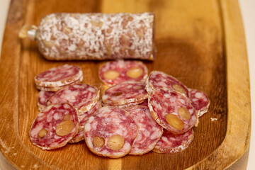 slices of fuet salami with walnuts on a wooden chopping board