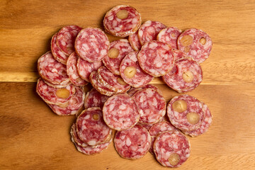 slices of fuet salami with walnuts on a wooden chopping board