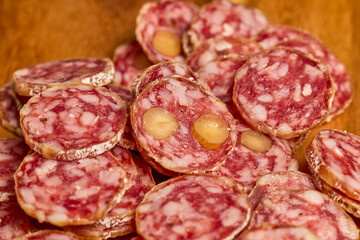 slices of fuet salami with walnuts on a wooden chopping board