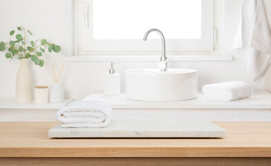 Stone tray with white towel on empty wooden table top in blur bathroom sink interior background