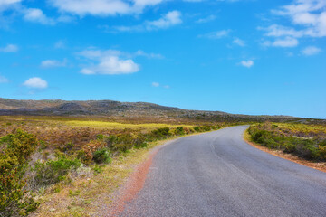 Road, blue sky and greenery with clouds for travel, countryside or trip in rural suburb. Empty,...