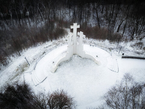 Aerial view of three crosses monument surrounded by snowy forest and tranquil landscape, Vilnius, Lithuania.