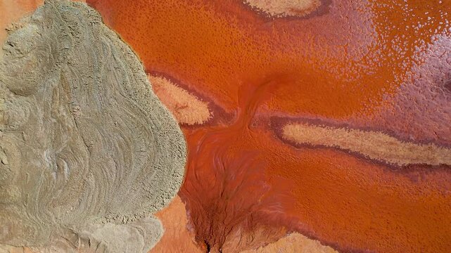 Aerial view of abstract patterns in vibrant orange and red at Redbank salt farm, Port Hedland, Australia.
