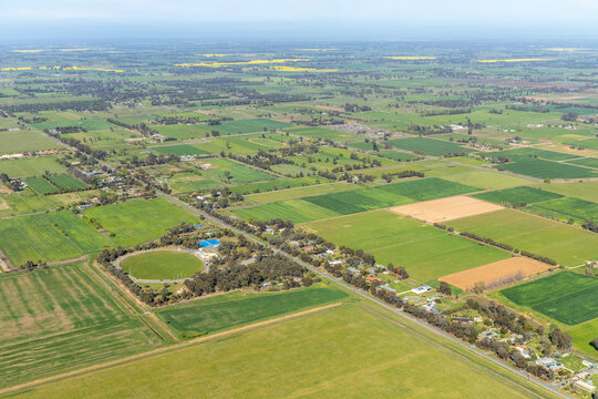 Aerial view of beautiful rural farmland with expansive green fields, trees, and a village, Lancaster, Victoria, Australia.