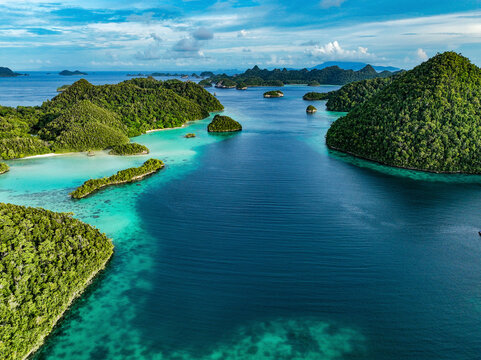 Aerial view of beautiful tropical islands and azure blue water in a serene lagoon, Raja Ampat Regency, Indonesia.