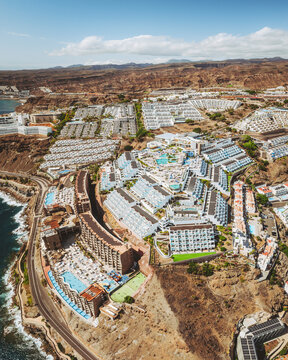 Aerial view of beautiful Puerto Rico de Gran Canaria hotels along the coast with tropical landscape and ocean, Mogan, Spain.