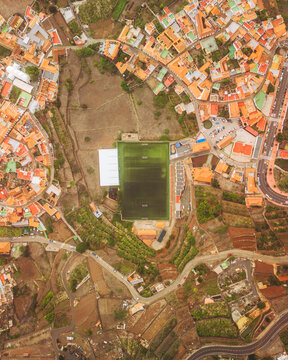 Aerial view of Agulo Stadium surrounded by colorful houses and green fields, Agulo, Spain.