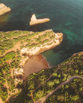Aerial view of Praia da Morena with rugged cliffs and blue waters, Porches, Portugal.