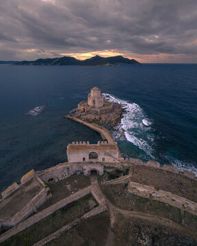 Aerial view of ancient medieval fortress with a tower by the beautiful coastline at sunrise, Methoni, Greece.