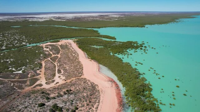 Aerial view of red sand beach and turquoise water at Roebuck Bay with mangroves, Broome, Australia.