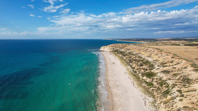 Aerial view of Port Willunga Beach with turquoise waters, sandy shore, and cliffs, Port Willunga, Australia.