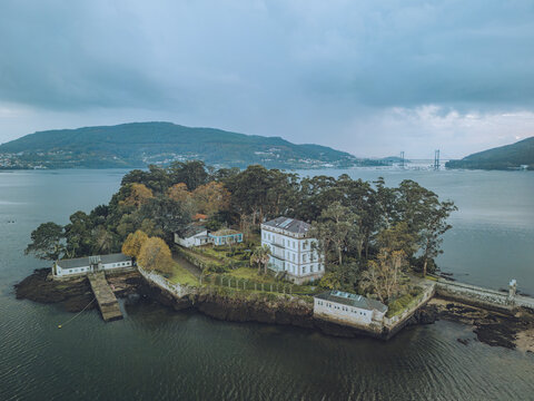 Aerial view of san simon island surrounded by tranquil water and lush trees, ria de vigo, spain.