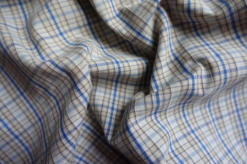 Brown, white, blue checkered cotton fabric in soft folds
