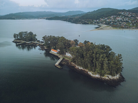 Aerial view of San Simon Island surrounded by tranquil waters and lush trees, Ria de Vigo, Spain.