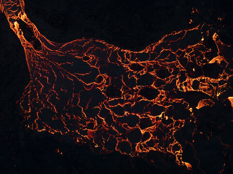 Aerial view of vibrant molten lava flowing from an active volcano with dramatic textures and patterns, Grindavik, Iceland.