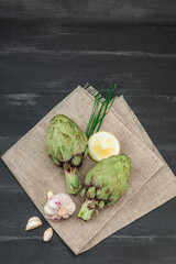 Fresh green artichokes cooking on wooden background. Traditional seasonal ingredients