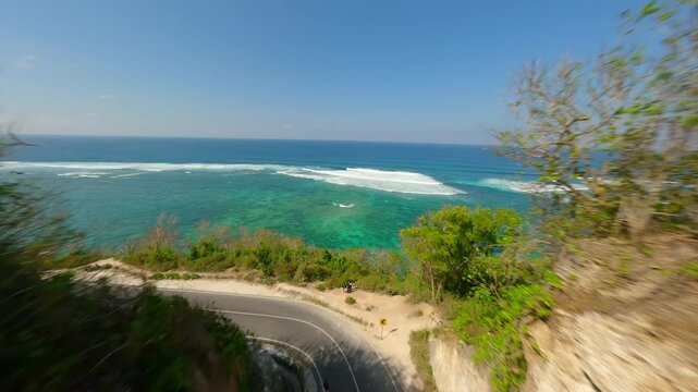 FPV flight over the road in limestone cliffs and the turquoise sea of Batu Barak beach in Bali, Indonesia