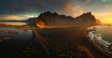 Aerial view of rugged mountains and serene ocean at sunset, Hofn, Iceland.