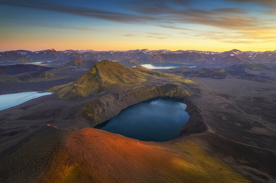 Aerial view of breathtaking volcanic mountains and a serene lake in a vibrant valley, Hella, Iceland.