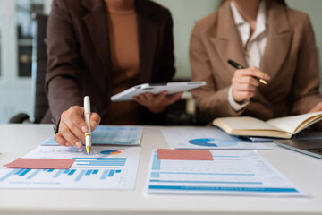 Business team analyzing documents, graphs, and data with a laptop, tablet, and smartphone. Collaboration, strategy, and success in a modern office.