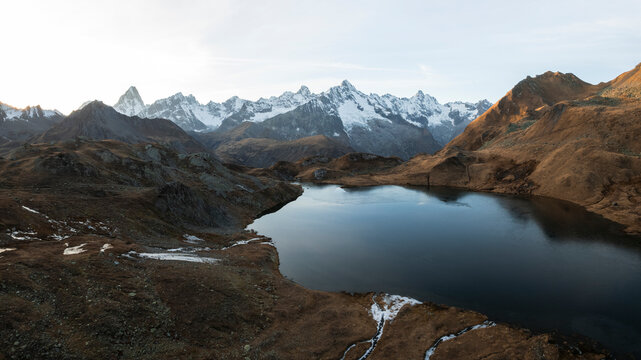 Aerial view of serene Lacs de Fenetre reflecting majestic mountains in autumn, La Fouly, Switzerland.