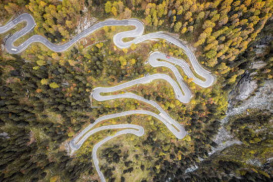 Aerial view of Maloja Pass with winding road through autumn forest and mountains, Maloja, Switzerland.