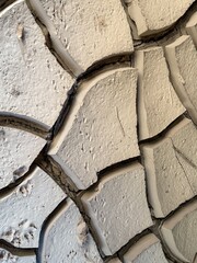 A cracked and weathered wall with a rough texture. The wall appears to be made of stone or concrete and has a weathered, aged look to it. The cracks and rough texture give the wall a sense of history