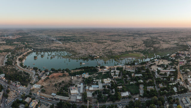 Aerial view of tranquil Amar Sagar Pol with serene lake and beautiful cityscape at dusk, Jaisalmer, Rajasthan, India.