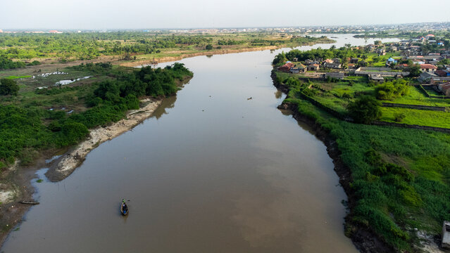 Aerial view of the serene Ogun River with lush greenery and a tranquil village, Ifo, Nigeria.