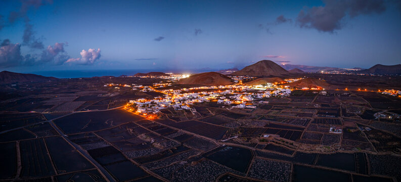 Aerial view of a traditional village illuminated at night with beautiful mountains and fields, Mancha Blanca, Canary Islands.