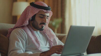 Young man in traditional attire working on laptop indoors