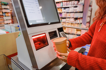 Customer scanning groceries at self checkout kiosk in supermarket