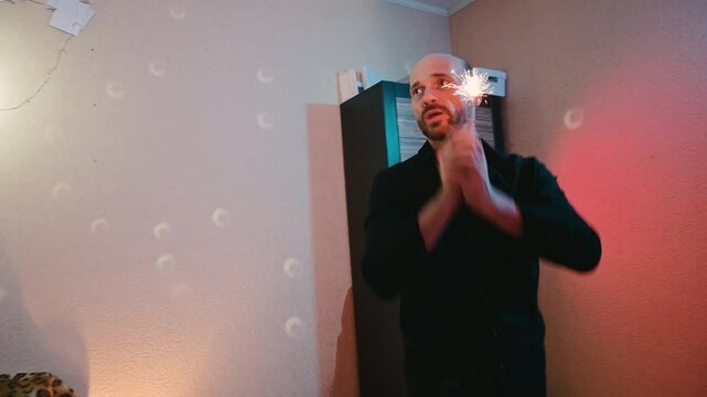 A man holds a sparkler in his hands. He enjoys the holiday.
