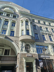 A three-story building with a pale yellow exterior and symmetrical windows, featuring a prominent arched entrance. The classical design evokes a sense of history and grandeur in urban architecture.