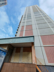 A tall apartment building with pastel-colored balconies and windows, located in a residential area. The structure captures the urban residential lifestyle, emphasizing functionality and density in