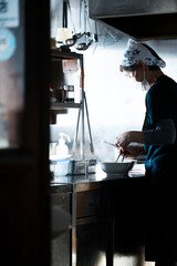 식당에서 손님들을 위해 정성껏 음식을 만드는 직원의 실루엣을 담은 사진입니다.