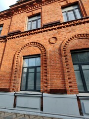 Detailed shot of an old red brick facade featuring arches and framed windows. The historic design emphasizes durability, symmetry, and urban aesthetic.
