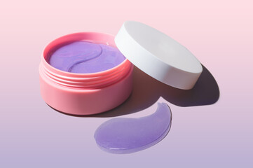 Cosmetic product purple glitter lavender eye patches in plastic jar. Gradient background.