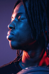 Focused close up view. African American guy is studio with neon lighting