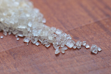 Close up macro of granulated sugar on a wooden table.