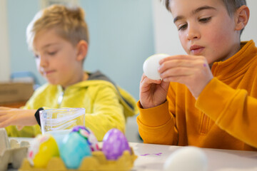 Two brothers are painting eggs for easter celebration at home