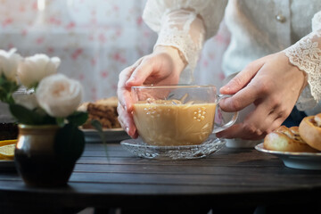 English morning breakfast. Woman drinking cup of tea with milk in cozy kitchen.