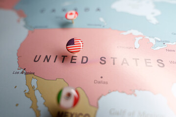  US flag push pin marking the United States on a map, with Mexico and Canada location pins visible