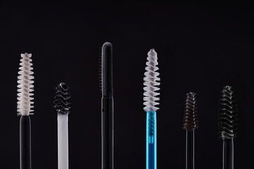 Selection of various brow gel and mascara brushes on black background