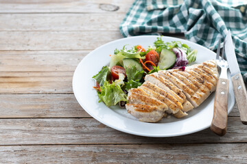 Healthy grilled chicken with salad on wooden table. Copy space