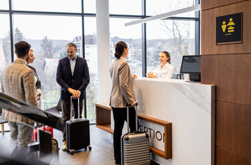 Group of business people arriving in a hotel for a business conference, checking in at the...
