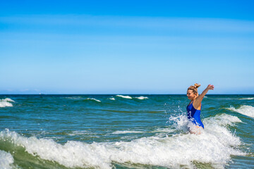 Beautiful mature woman enjoying bathing in big waves in sea in summertime