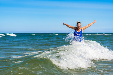 Beautiful mature woman enjoying bathing in big waves in sea in summertime