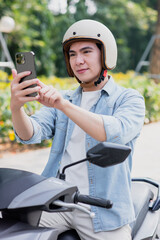 Fototapeta premium Asian man looks at map on phone while riding a motorbike 